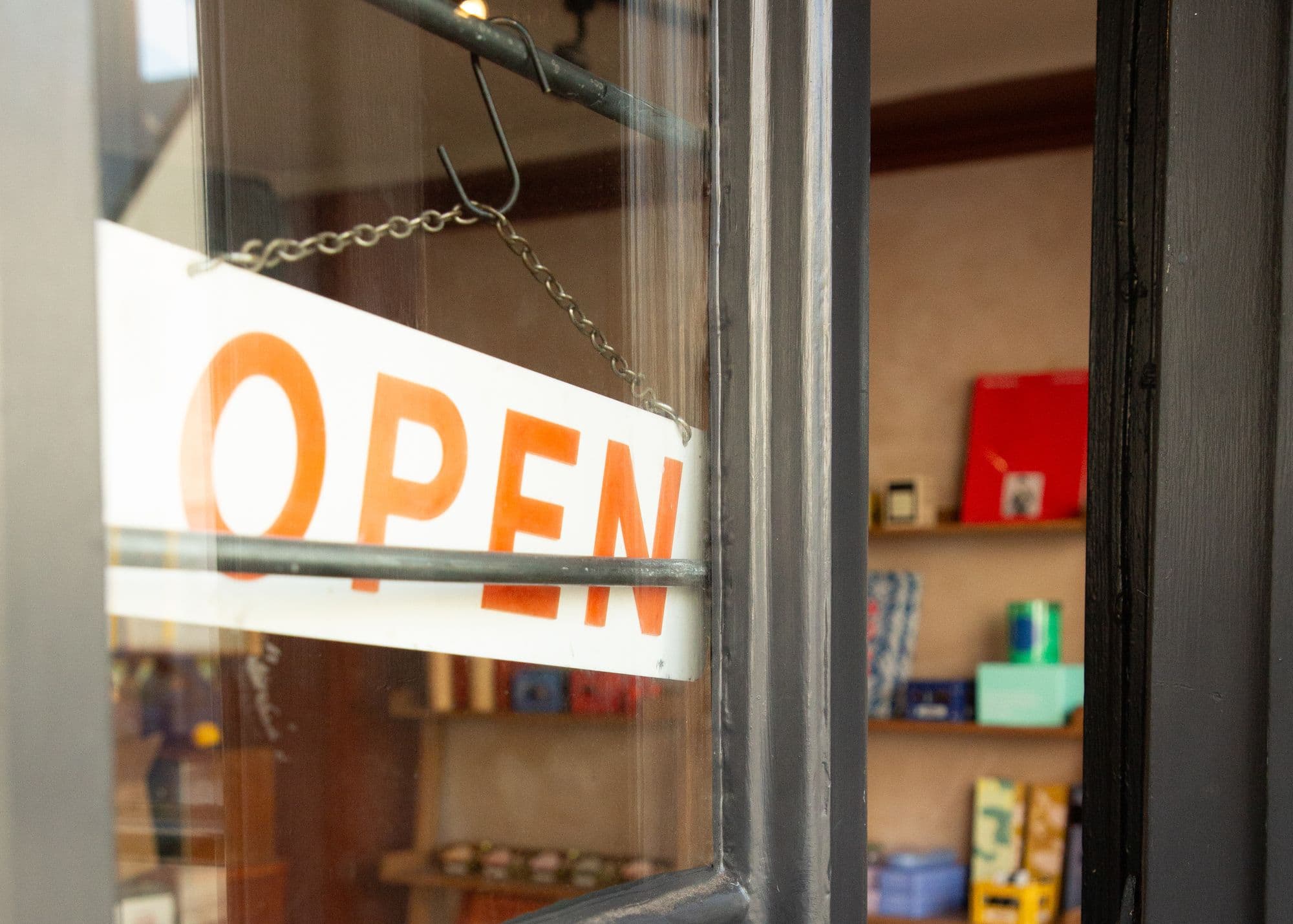 The glazed front door with an OPEN sign hanging inside, shop shelves visible through the glass