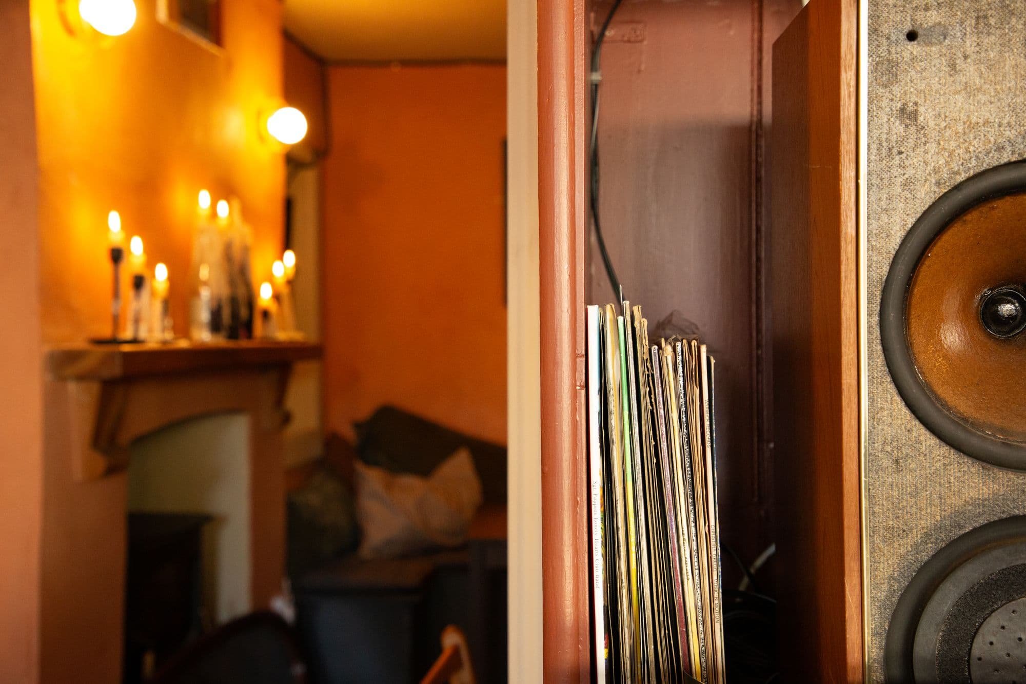 The snug by candlelight, candles along the mantelpiece, records and a speaker in the foreground