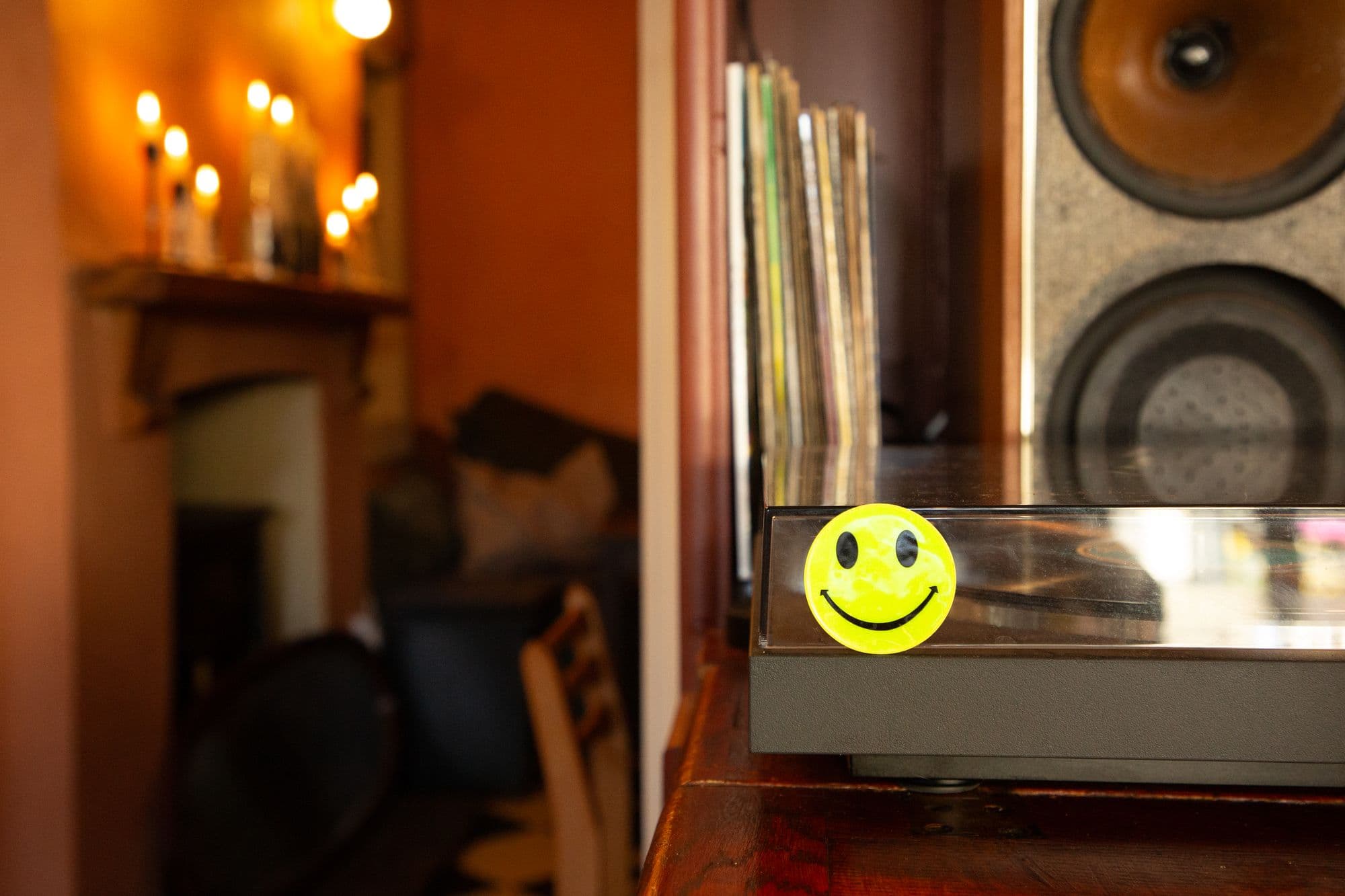 Candles burning along the snug mantelpiece, with record sleeves, a speaker and a turntable on the right